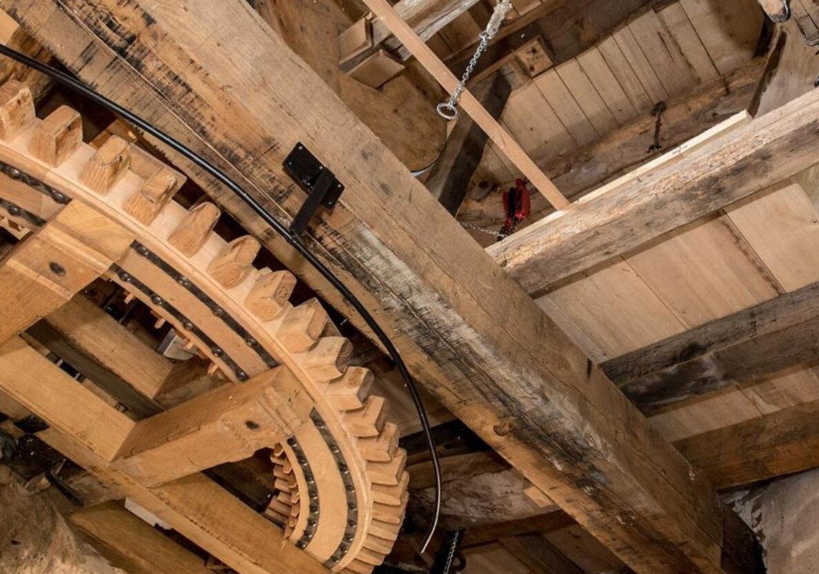 Un mecanismo de engranajes de madera de gran tamaño, probablemente parte de un reloj o dispositivo mecánico.