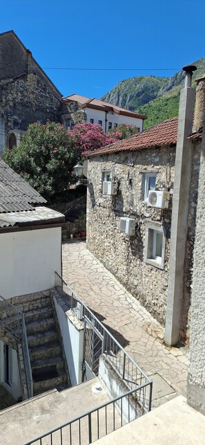 Un bâtiment en pierre avec un toit en tuiles, des unités de climatisation et un escalier menant à un étage supérieur.