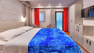 A hotel room with a bed, a TV, a wardrobe, and a window with curtains.