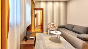 A modern living room with a sofa, a small round table, and a TV on a wooden stand.
