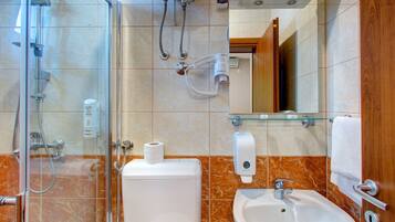 A bathroom with a glass shower enclosure, a toilet, a sink, and a mirror.