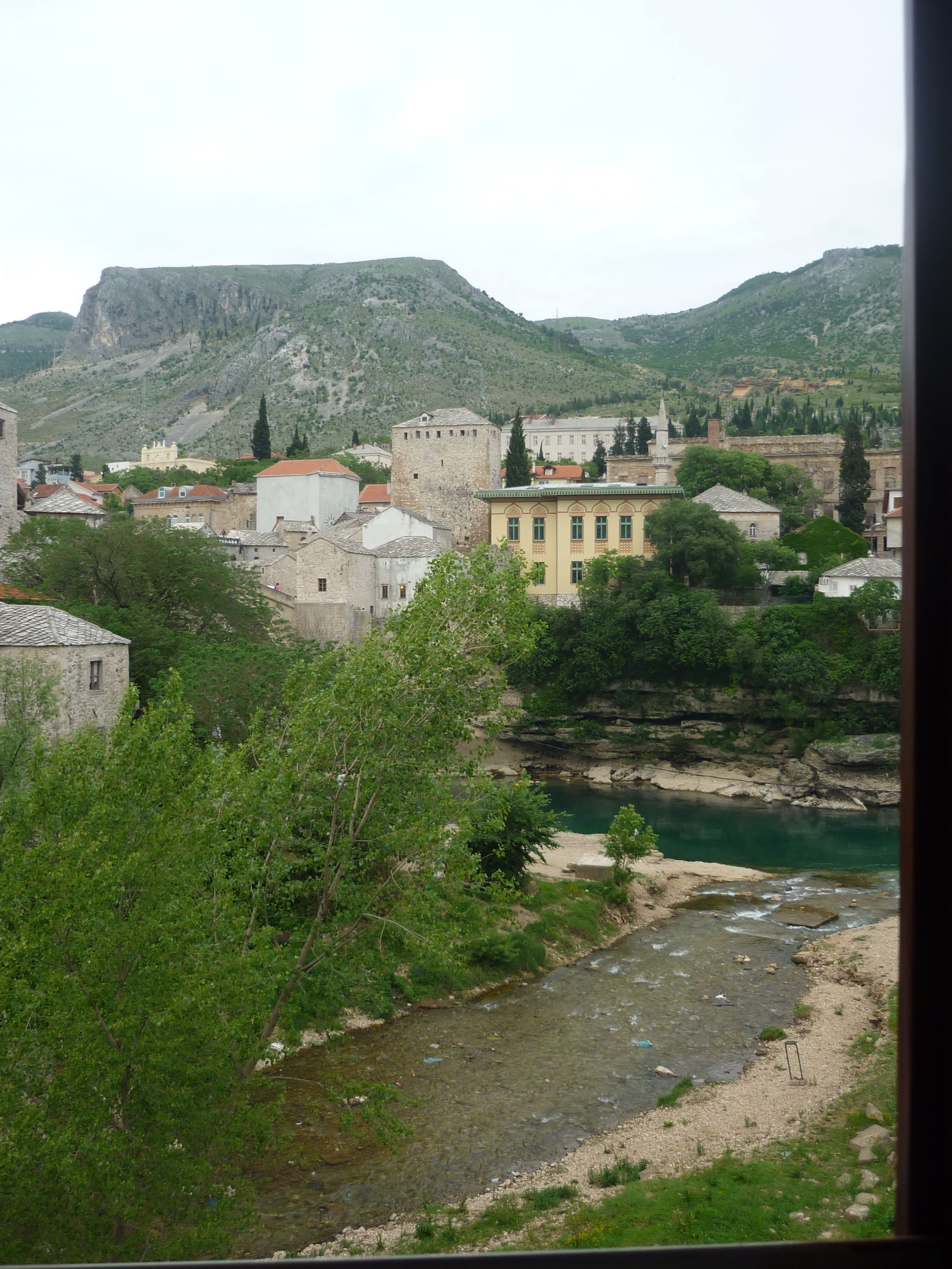 Une ville dotée de bâtiments historiques, traversée par une rivière, avec des montagnes en toile de fond.