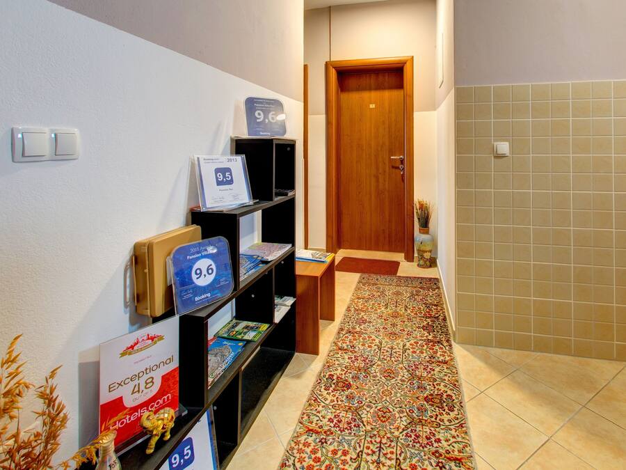 A hallway with a patterned carpet, a wooden door, and a shelf with various informational brochures.