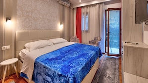 A modern bedroom with a large bed, a TV, and a sliding glass door to the outside.