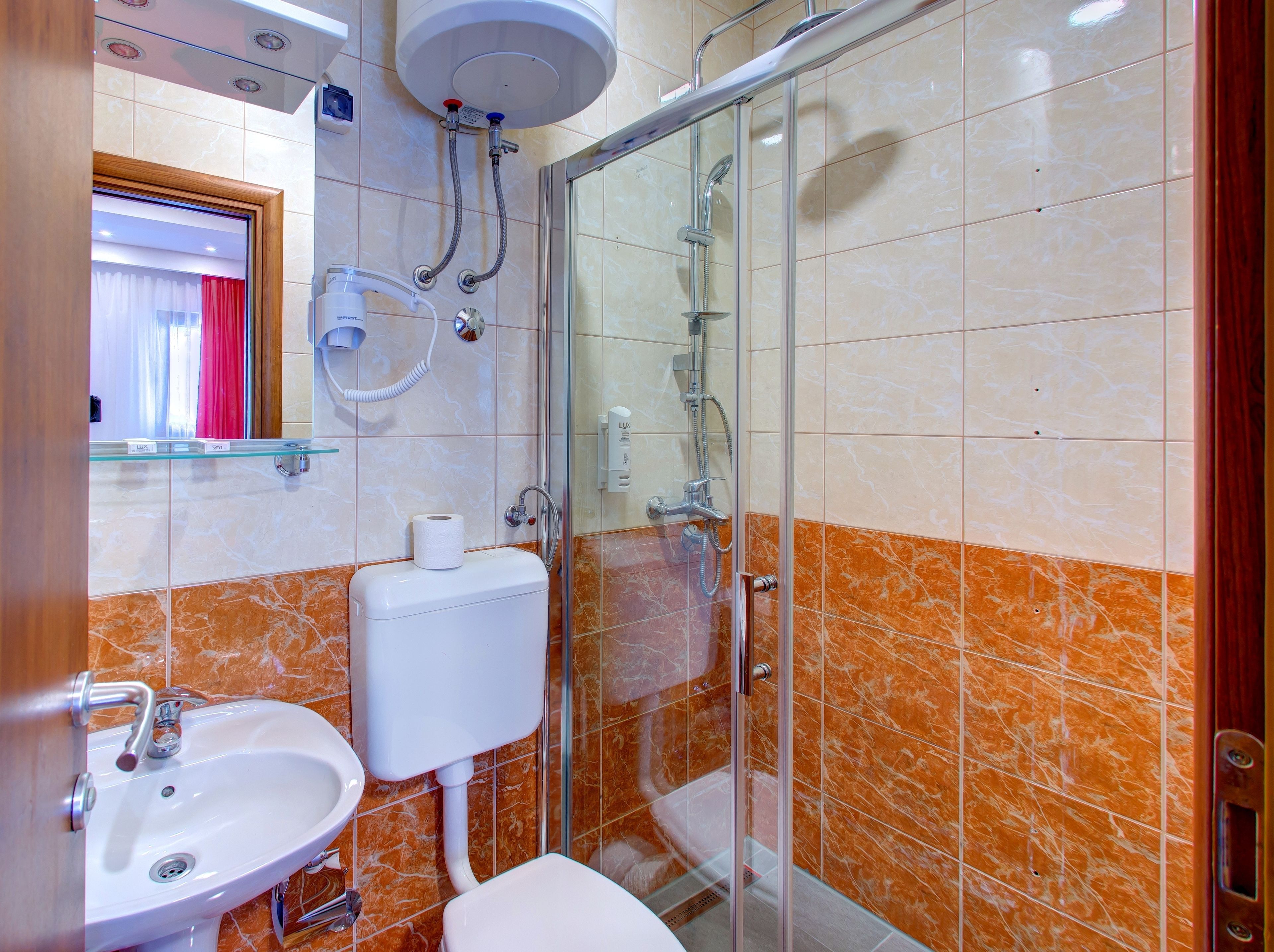 A bathroom with a glass shower enclosure, a toilet, a sink, and a towel rack.