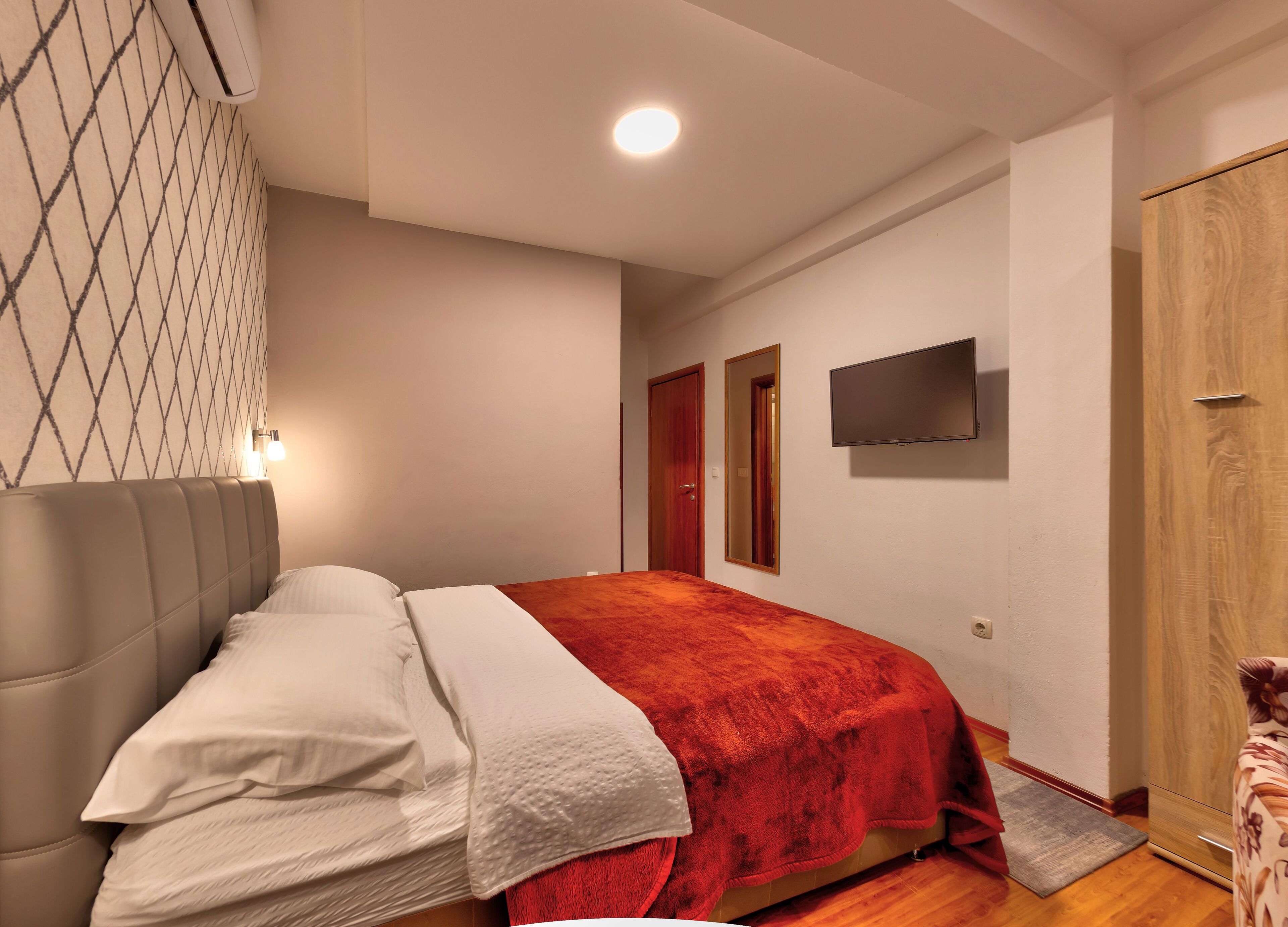 Ein Schlafzimmer mit einem Bett, einem Fernseher, einem Kleiderschrank und einer Tür.