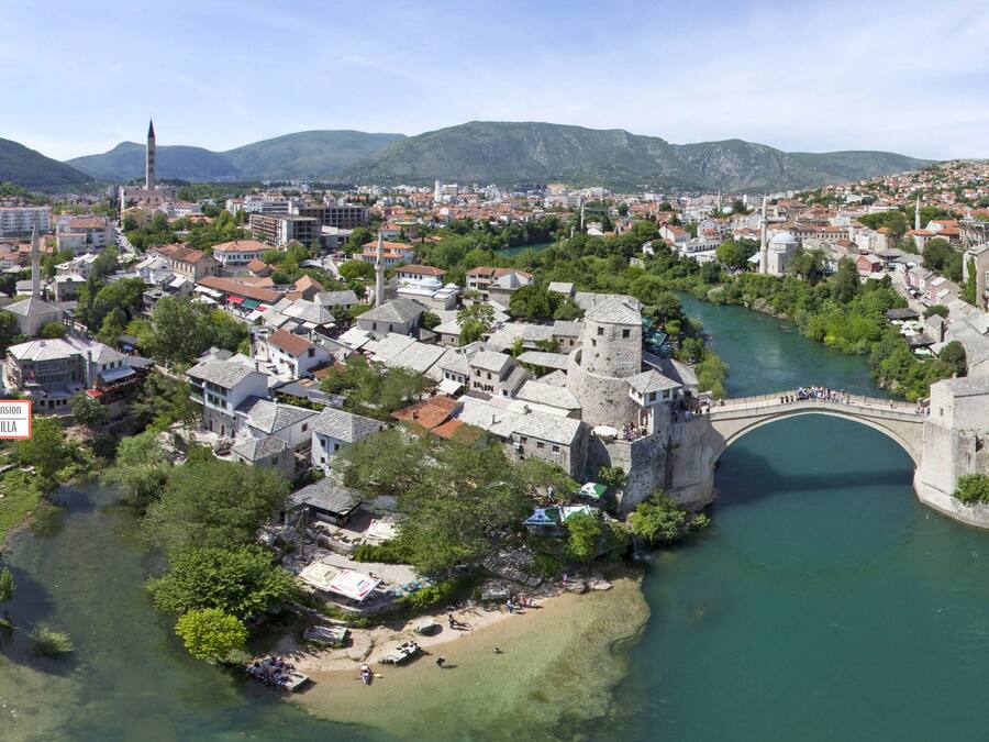 A historic town with a river, stone buildings, and a bridge.
