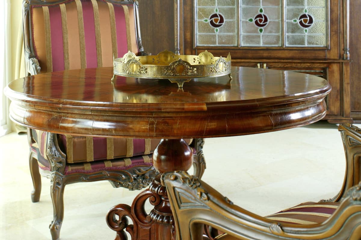 Une pièce comprenant une table à manger en bois, une chaise à motifs rayés, un lustre et un grand buffet en bois doté de panneaux de verre.