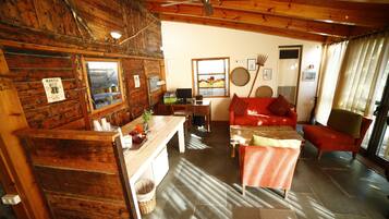 Interior rústico de una cabaña con una zona de comedor de madera, un sofá rojo y un ventilador de techo.
