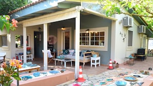A covered patio area with outdoor seating, a fire extinguisher, and decorative bowls. - Simatos Apartments and Studios (Kefalonia)