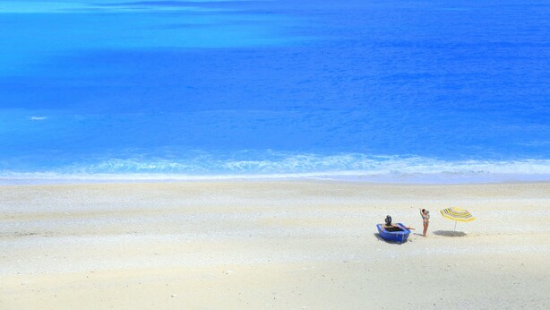 A beach with a boat and an umbrella. - Simatos Apartments and Studios (Kefalonia)