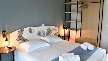 A neatly made bed with white linens, a bedside lamp, and a wall with a leaf pattern.