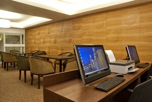 A hotel reception area with wooden paneling, multiple computer workstations, and seating arrangements.
