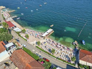 An aerial view of a beach with clear waters, numerous boats, and umbrellas. - Garni Hotel Milica (Denovici)