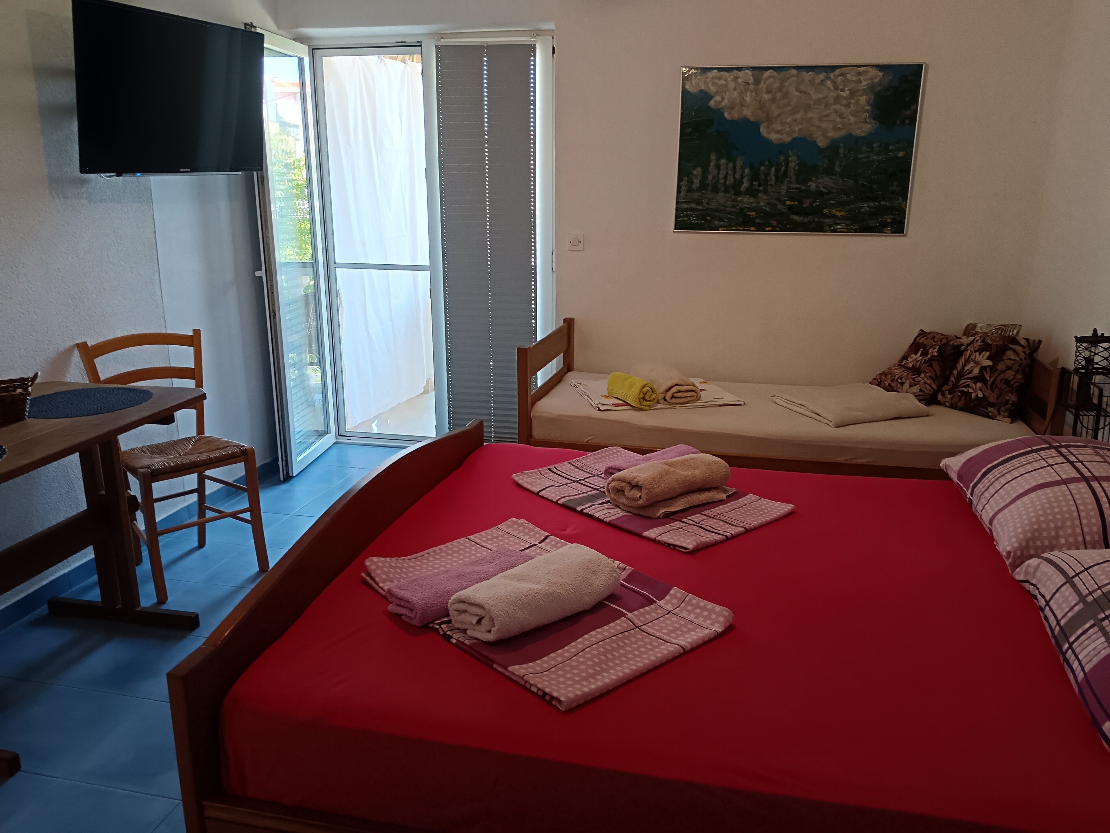 Une pièce comprenant un lit, une table, une chaise, un tableau et une porte coulissante.