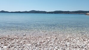 A pebble beach with clear water and distant hills. - Apartments Moreta (Biograd na Moru)