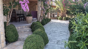 A patio area with a stone pathway, potted plants, and a seating area with a table and chairs. - Apartments Moreta (Biograd na Moru)