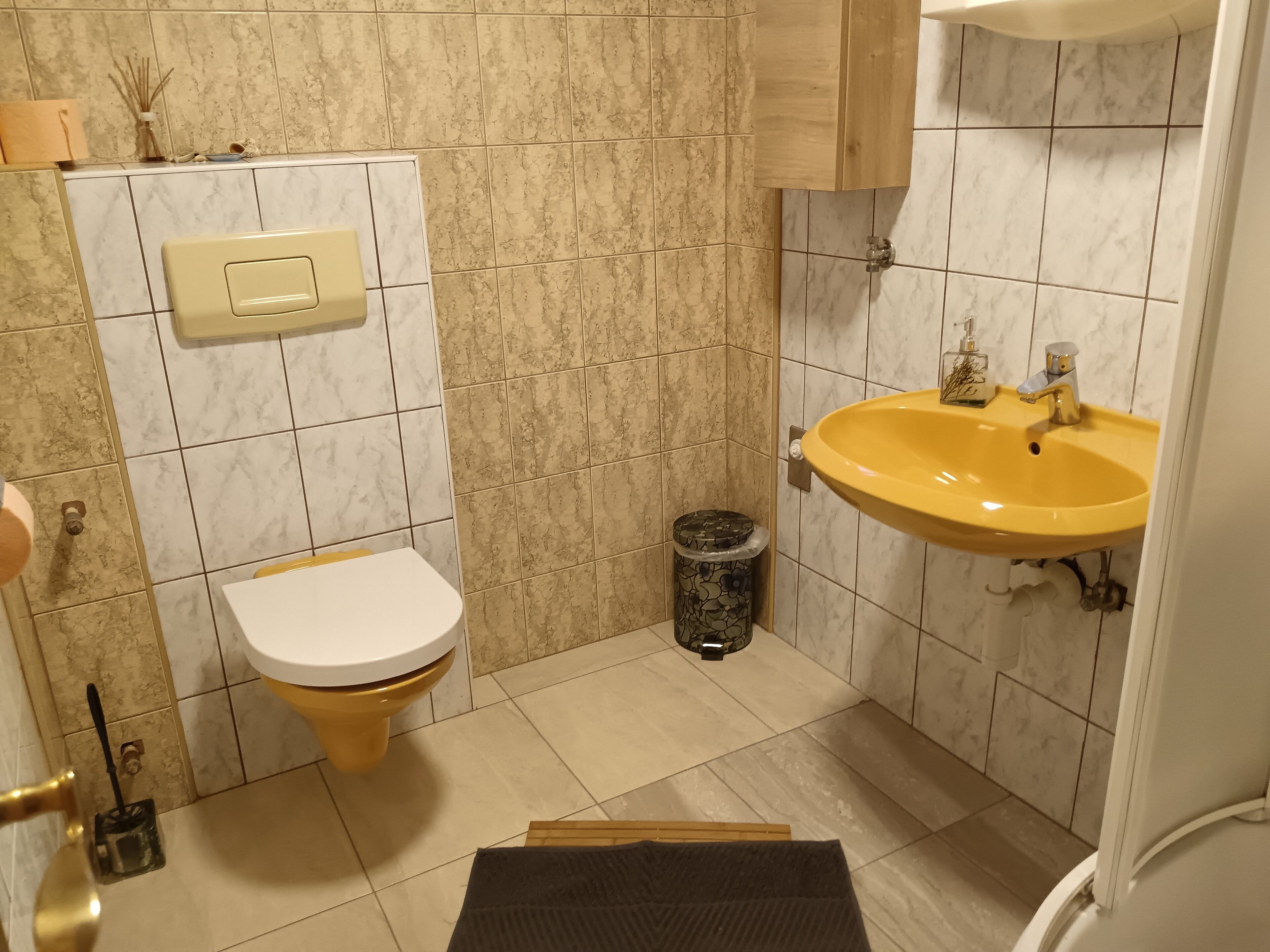 Casa de banho com sanita, lavatório e lixeira.