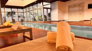A modern indoor pool area with wooden flooring, large windows, and a view of trees. - Design Suites Buenos Aires (Buenos Aires)