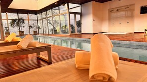 Una piscina techada, sillones reclinables de piscina