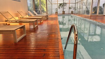 Una piscina techada, sillones reclinables de piscina