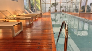Una piscina techada, sillones reclinables de piscina