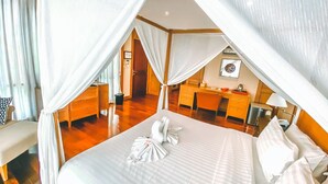 A bedroom with a canopy bed, a desk, and a chair.