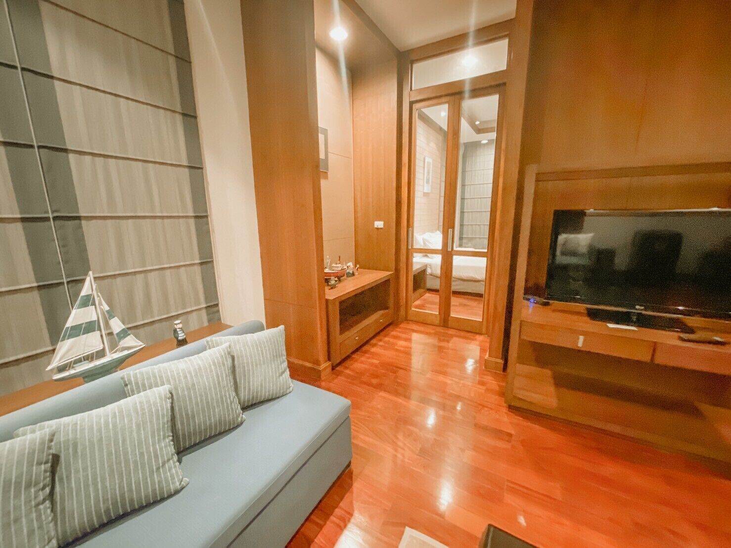 Ein modernes Wohnzimmer mit grauem Sofa, Holzboden, einem Fernseher und einem kleinen Tisch mit Dekoration.