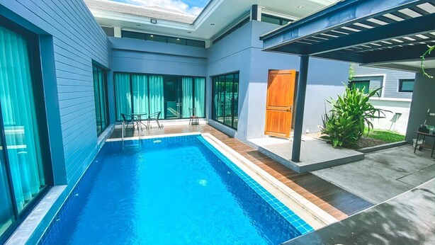 A modern house with a swimming pool, a covered patio, and a door.