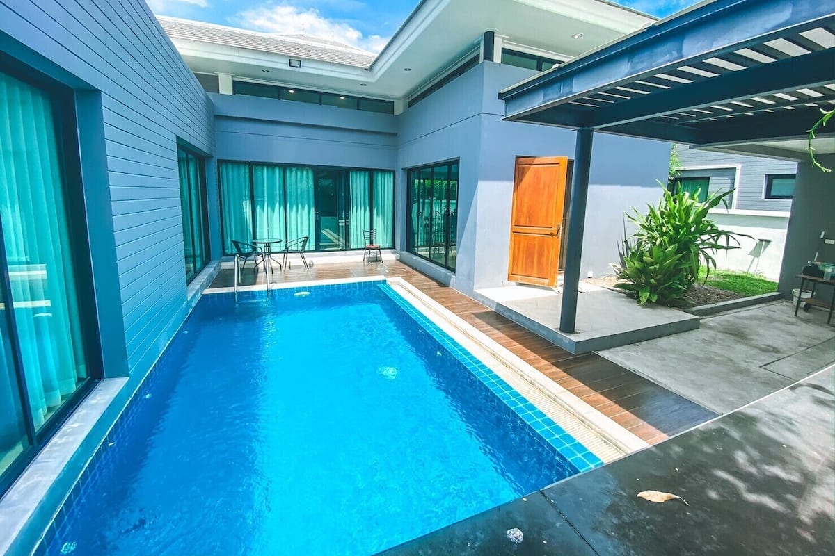 Uma casa moderna com piscina, alpendre coberto e uma porta.
