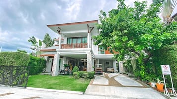 A modern two-story house with a balcony, a driveway, and a no-entry sign.