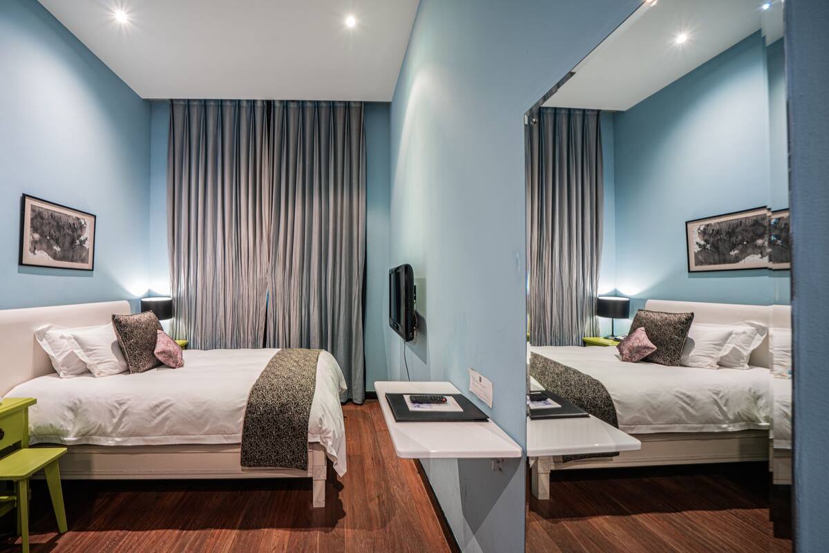 A mirrored room with two beds, a desk, and a phone.