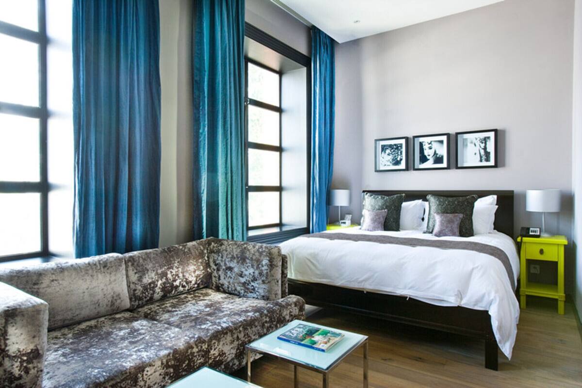 A bedroom with a large bed, a sofa, and a bedside table.