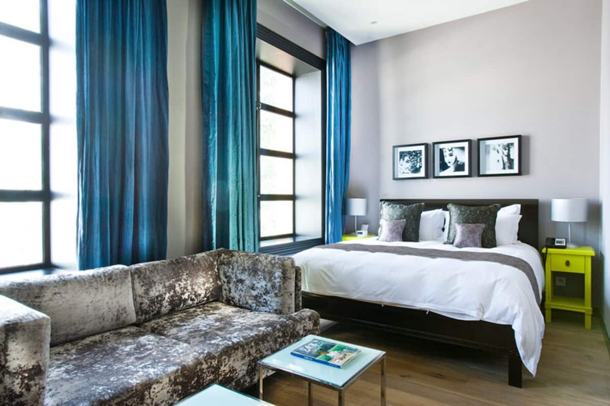 Un dormitorio con una cama grande, un sofá y una mesita de noche con lámpara.