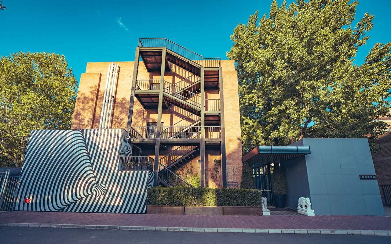 A multi-story building with a prominent staircase and a large, striped sculpture in the foreground.