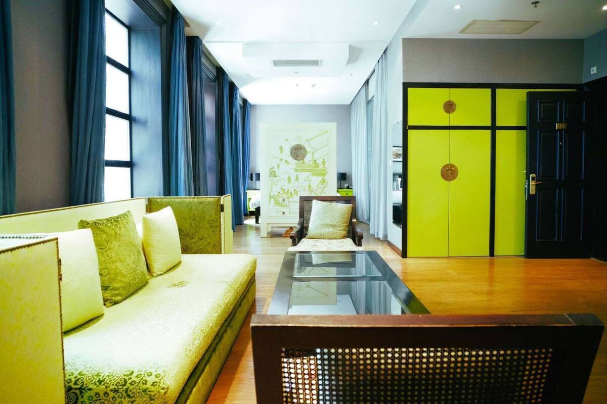 A modern hotel lobby with a sofa, a coffee table, and a bright green door.