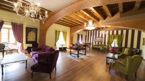 A spacious living room with wooden floors, a chandelier, and striped wallpaper. - Hotel San Antón Abad (Villafranca Montes de Oca)