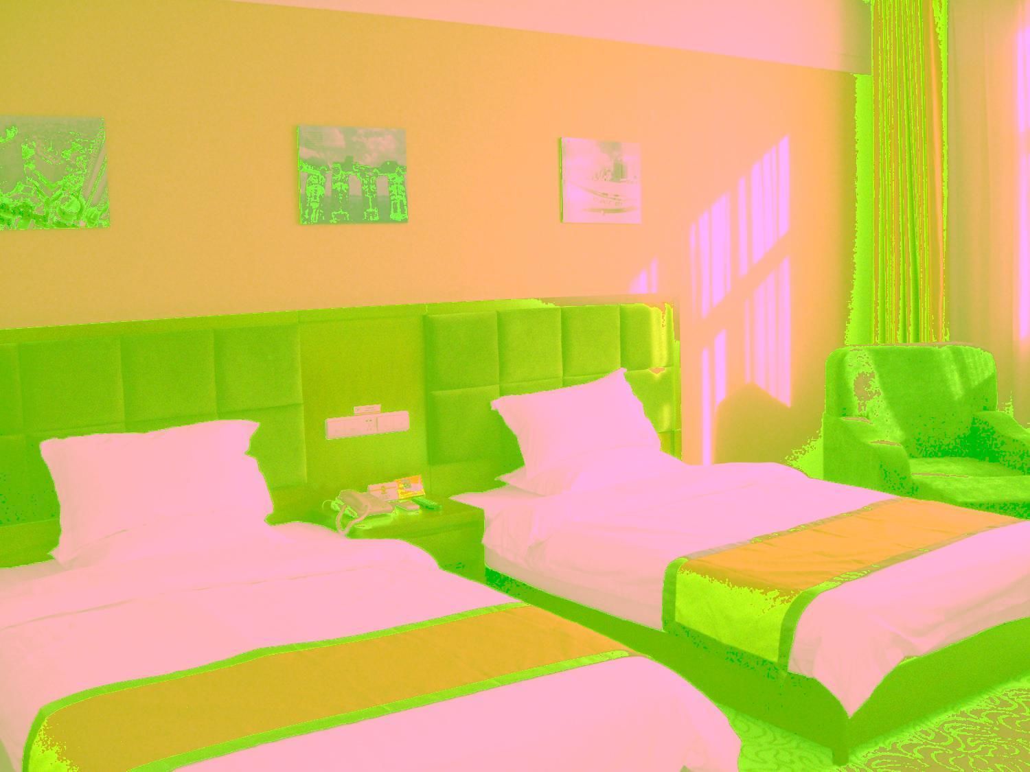 A hotel room with two beds, a green headboard, a nightstand, and a chair.