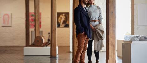 Una habitació àmplia amb bigues de fusta, una pissarra i obres d'art a les parets.