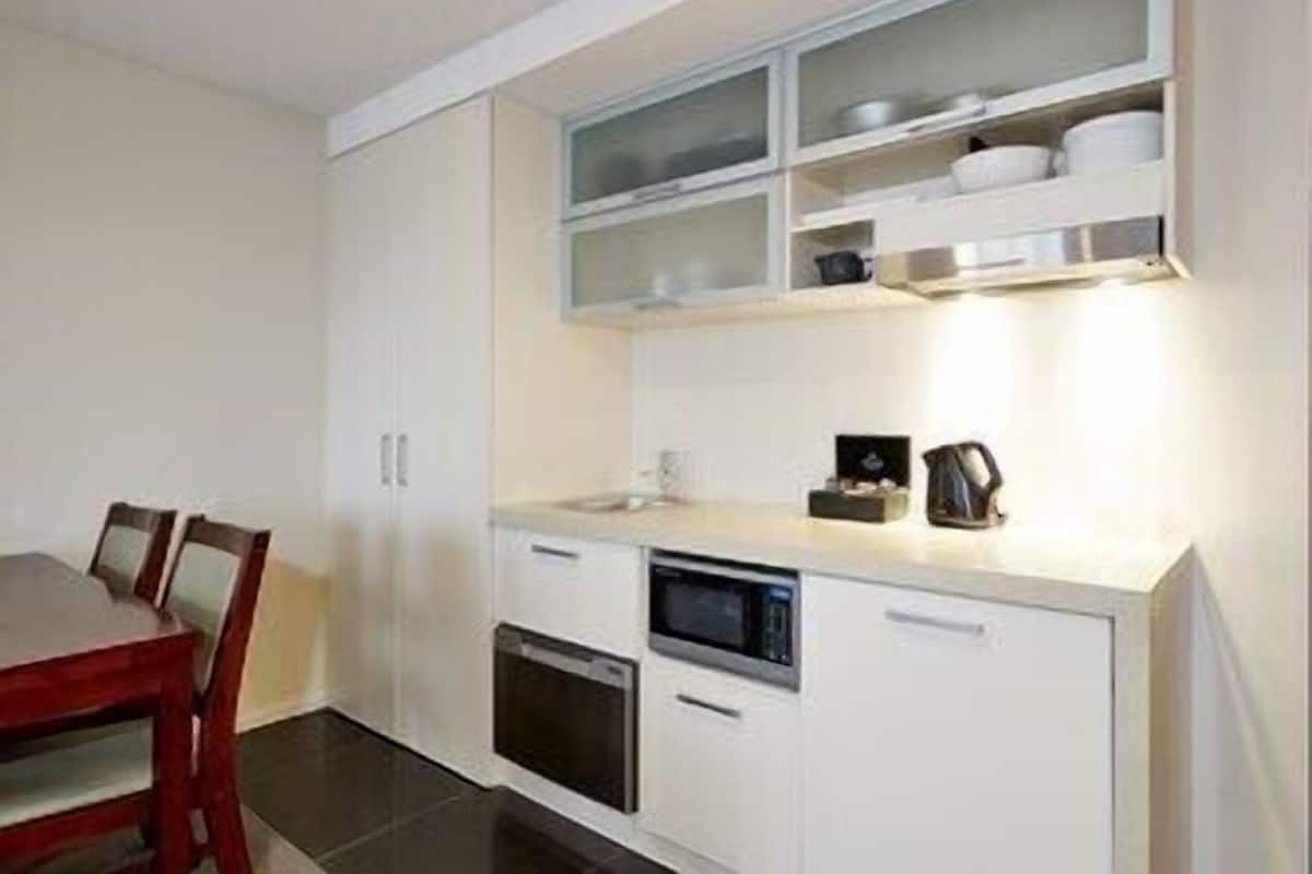 A compact kitchen with white cabinetry, a microwave, an oven, and a small countertop area.