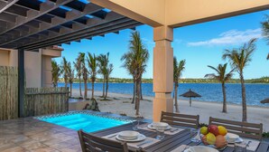 A poolside dining area with a view of the beach and water.