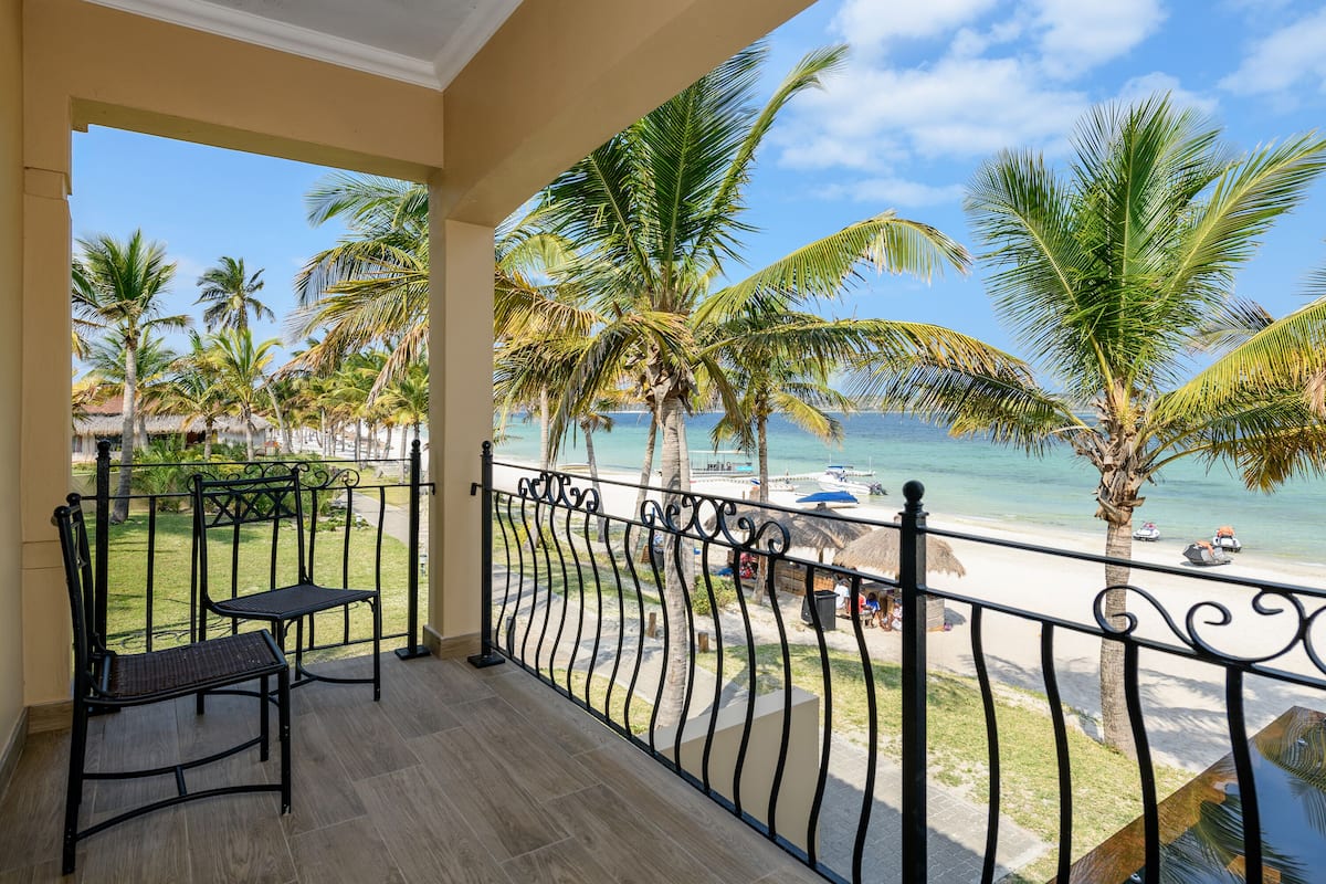 Un balcon avec vue sur la plage, les palmiers et un ciel dégagé.