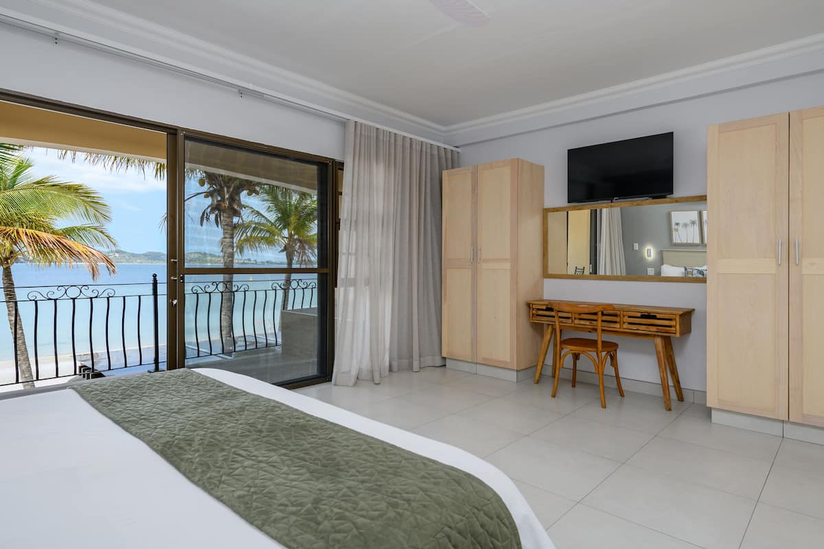 Une chambre d’hôtel avec un balcon, un lit, un bureau et une télévision.