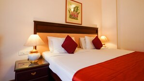 Una camera d'albergo con un letto grande, due abat-jour, un comodino e un quadro appeso al muro.