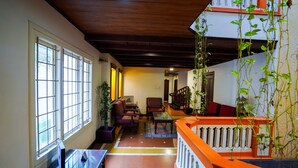 Un'ampia zona giorno con soffitto in legno, ampie finestre e un balcone con piante.