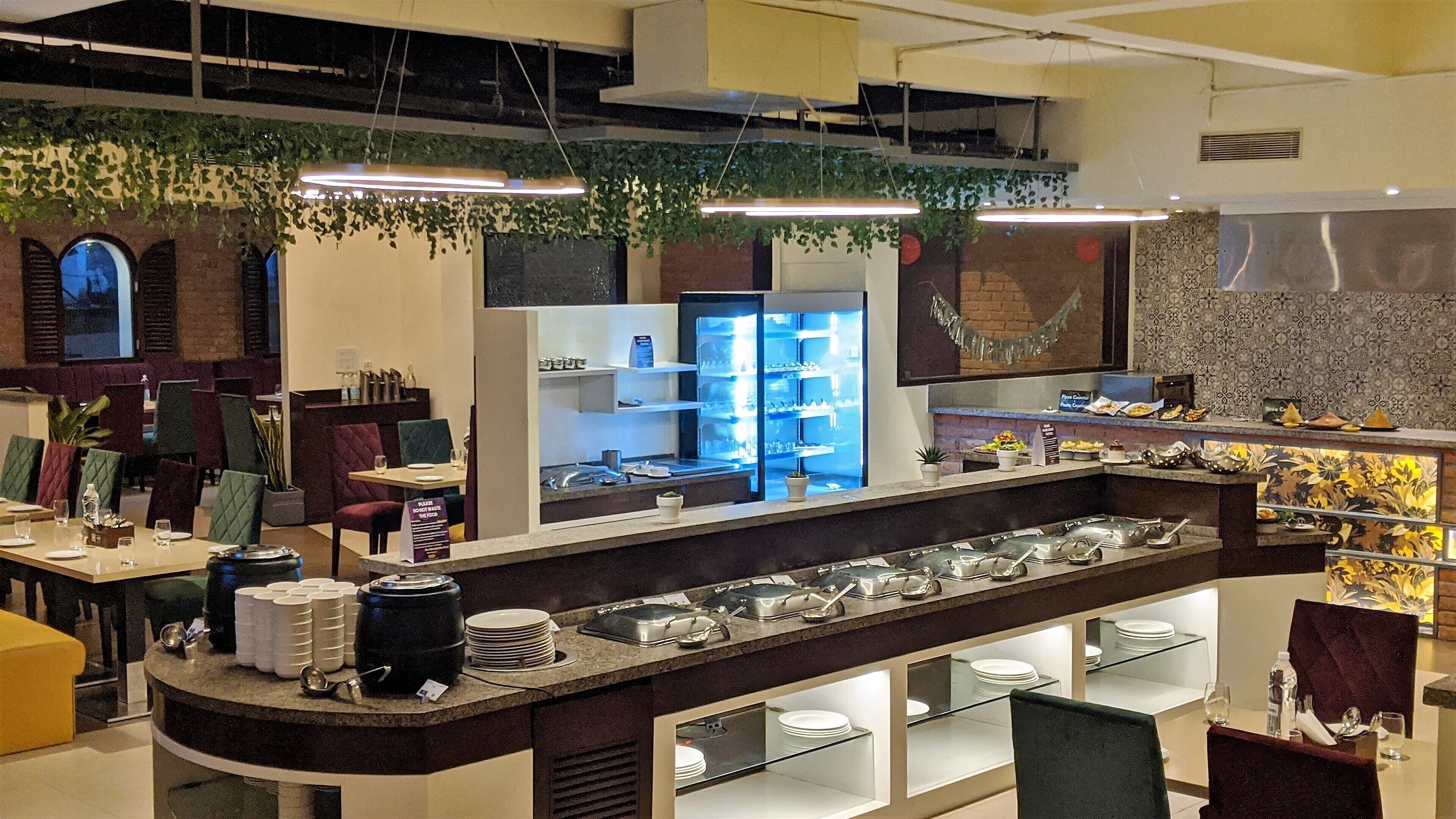 Een modern restaurant met een lange toonbank, glazen vitrines en verschillende zitmogelijkheden.