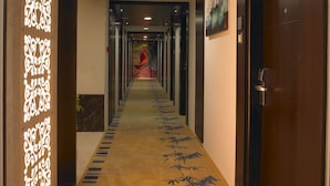 Un couloir d’hôtel avec un mur orné d’un motif, une moquette à motifs de bambou et un tableau accroché au mur.