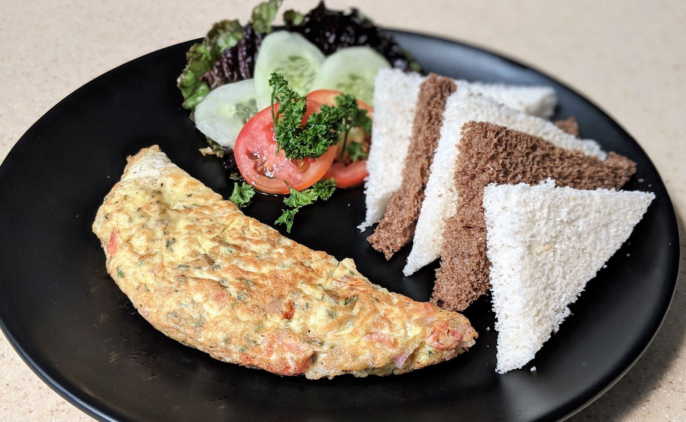 A plate with a slice of toast, a piece of bread, a slice of cake, and a small salad.