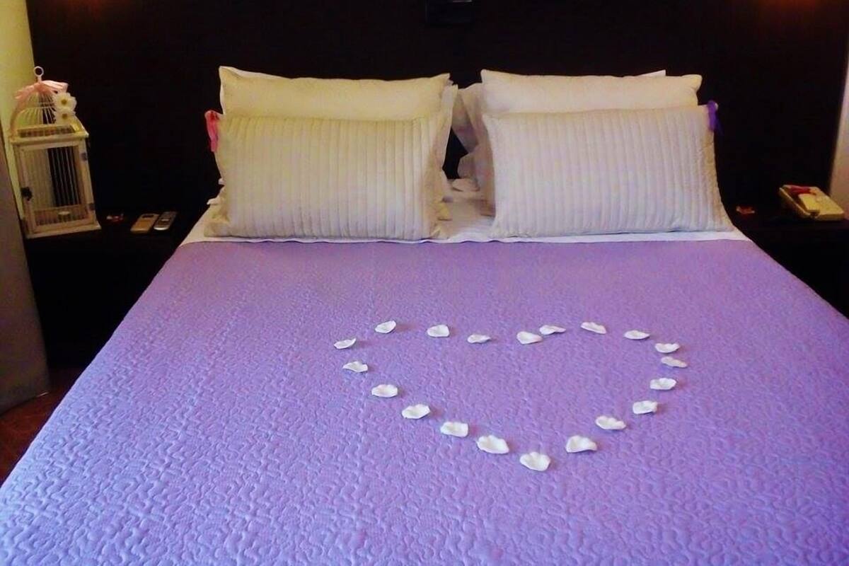 A bed with white pillows and a purple bedspread.