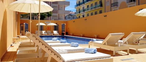 Piscine extérieure, parasols de plage, chaises longues